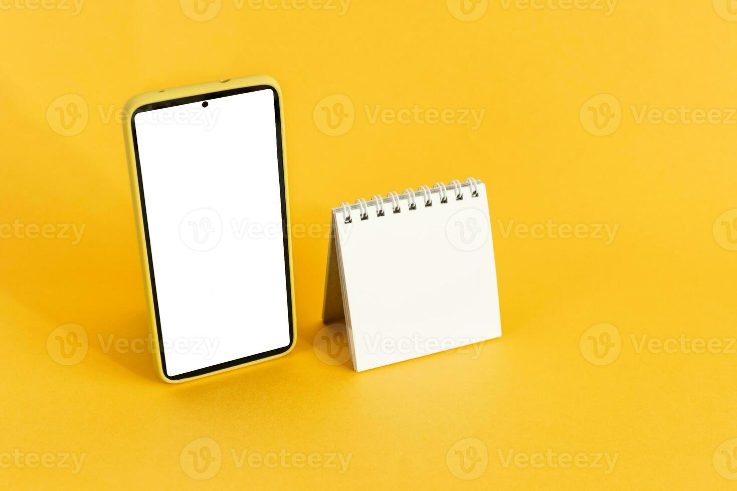 Blank calendar and smart phone, on yellow background. Schedule Planning. photo