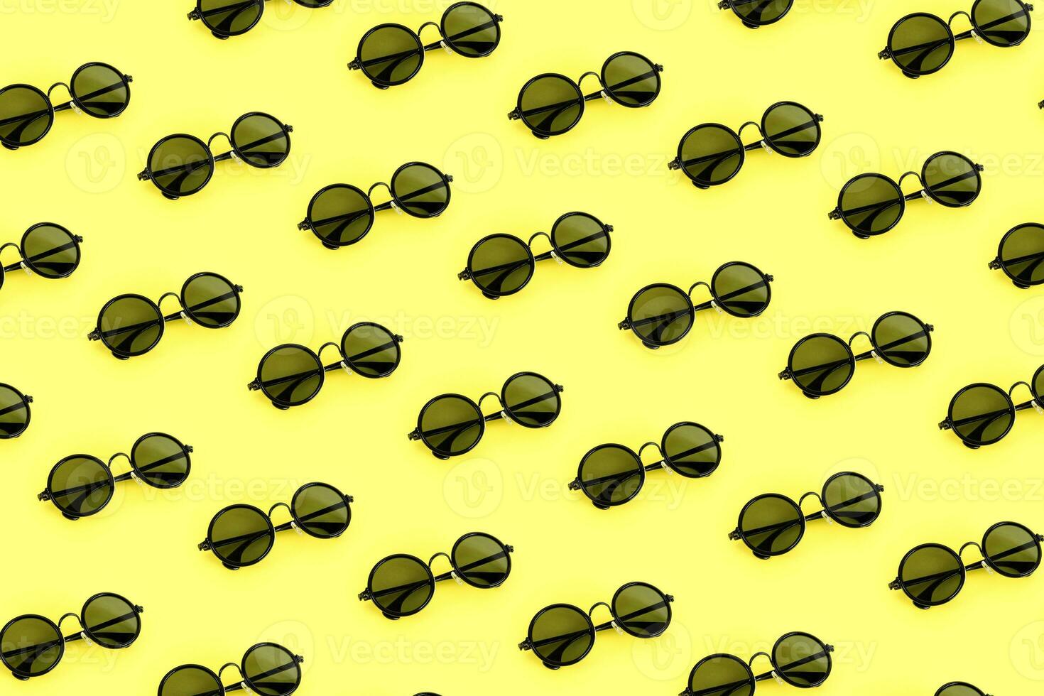 Black sunglasses pattern on pastel yellow background. Minimal summer concept. photo