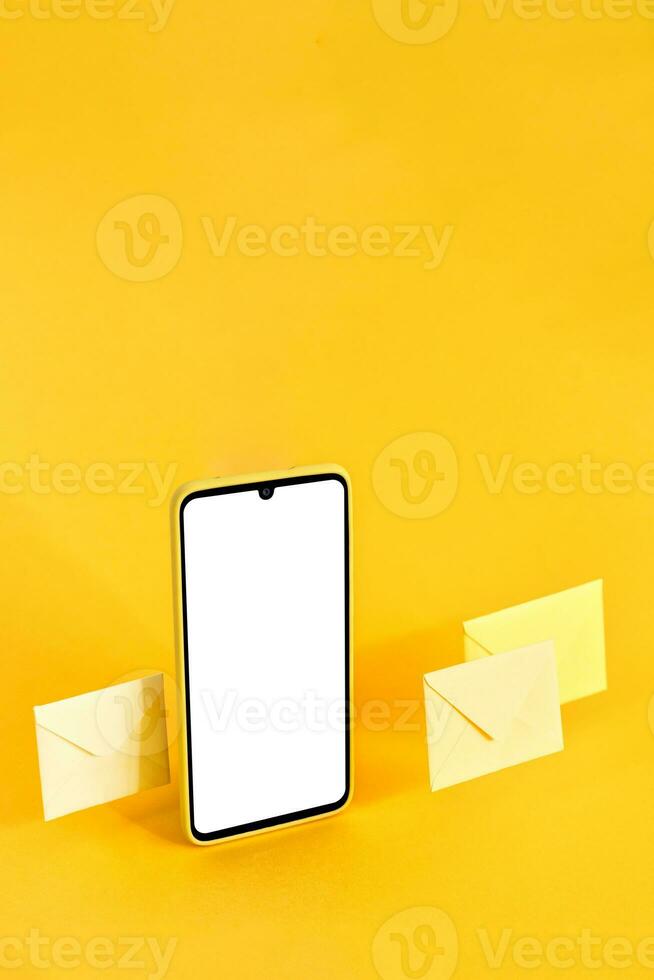 Smart phone and envelopes on yellow background. Online communication concept. photo