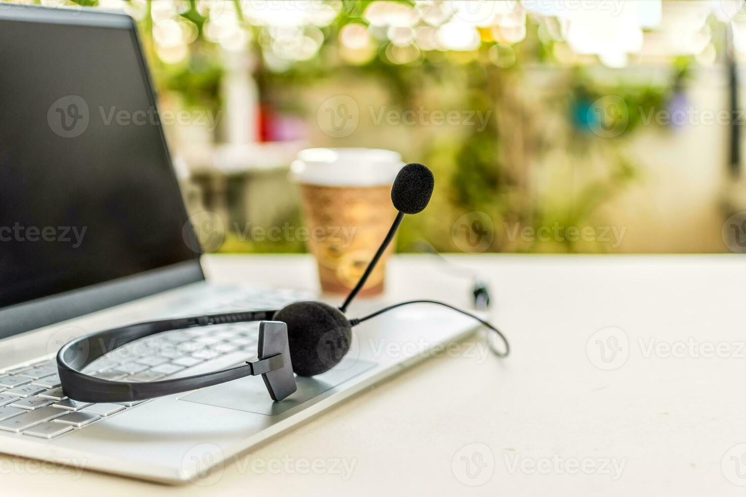 Headset with microphone on keyboard computer laptop, on desktop. Call center support concept. photo