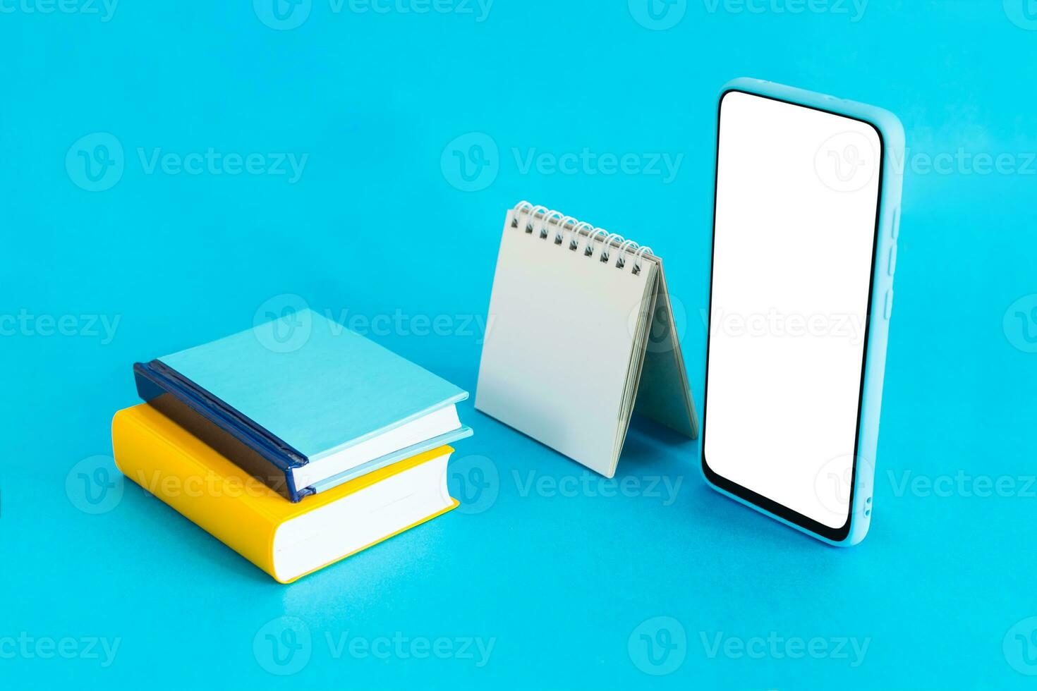 Blank calendar, notebook and smart phone, on light blue background. E-learning and Schedule Planning concept. photo