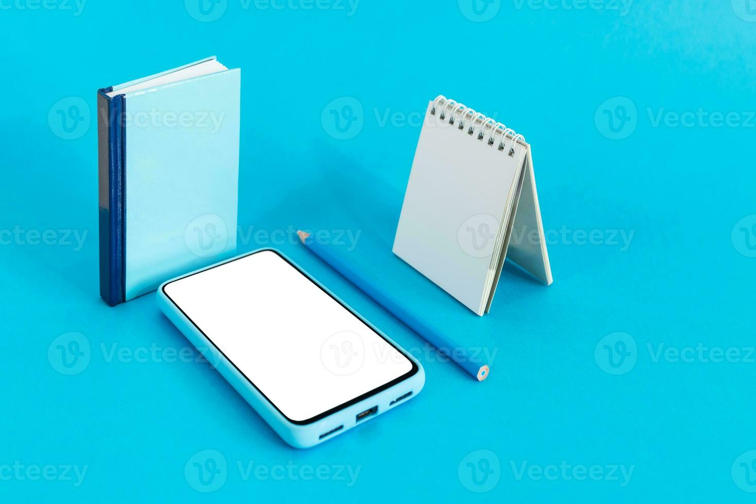 Blank calendar, notebook, pencil and smart phone, on light blue background. E-learning and Schedule Planning concept. photo