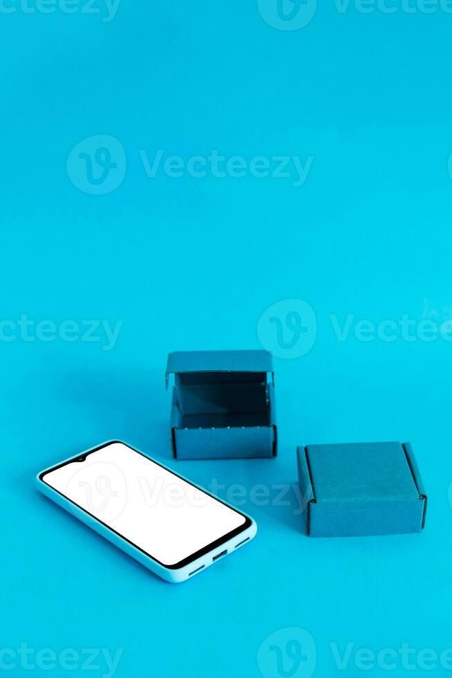 Isometric view of mobile phone and two boxes on light blue background. Shopping online.. photo