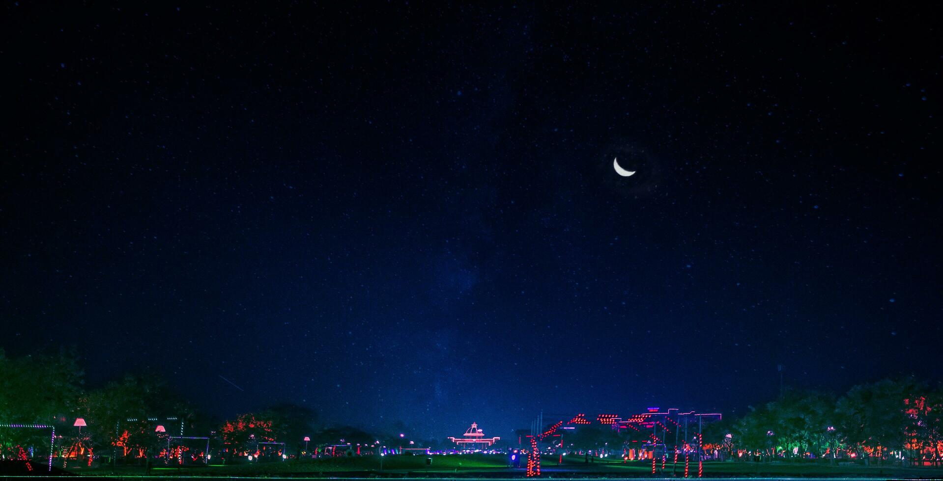 a park with a tree and a moon in the sky photo