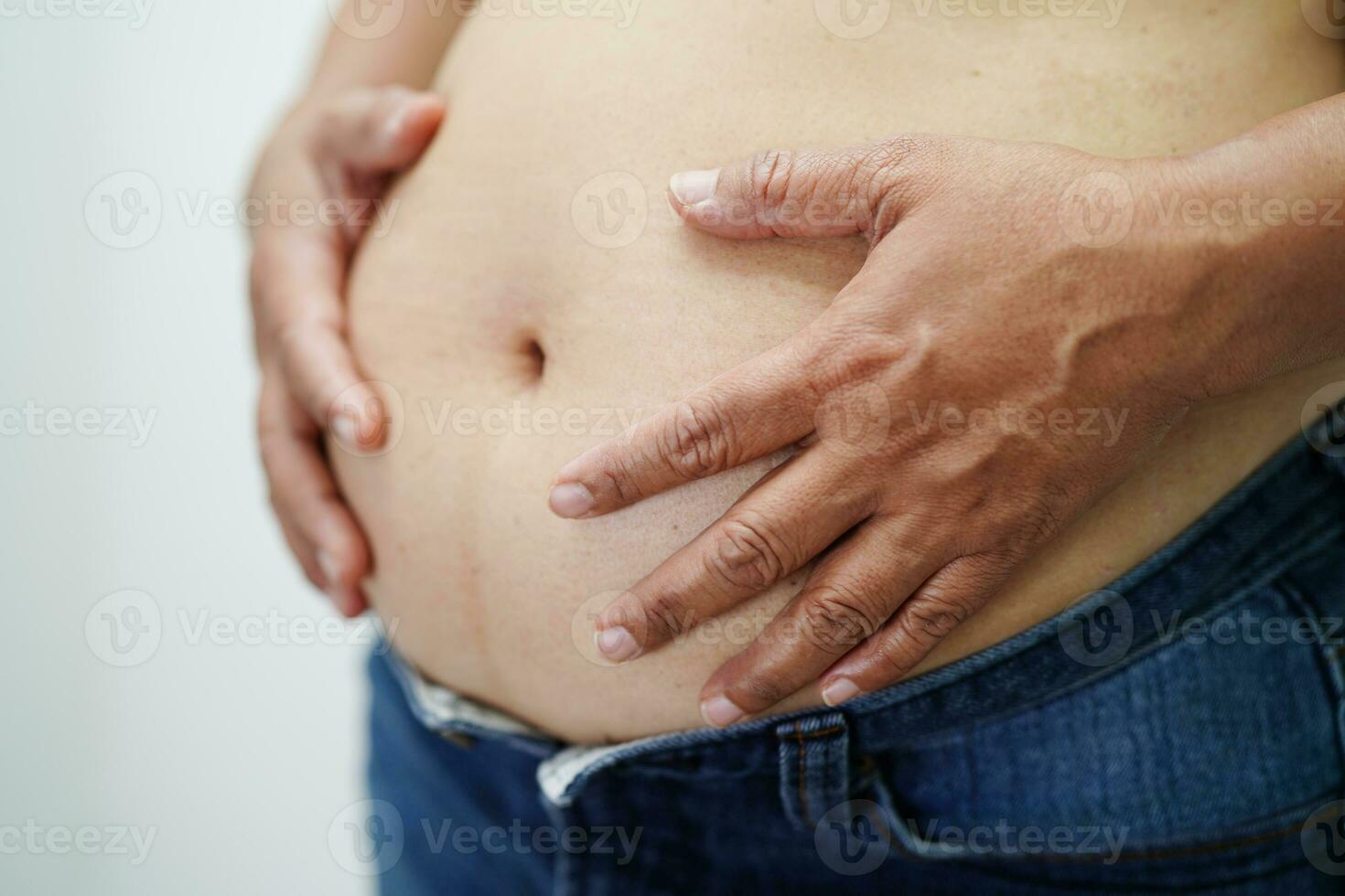 la mujer asiática muestra un vientre gordo de gran tamaño con sobrepeso y obesidad en la oficina. foto