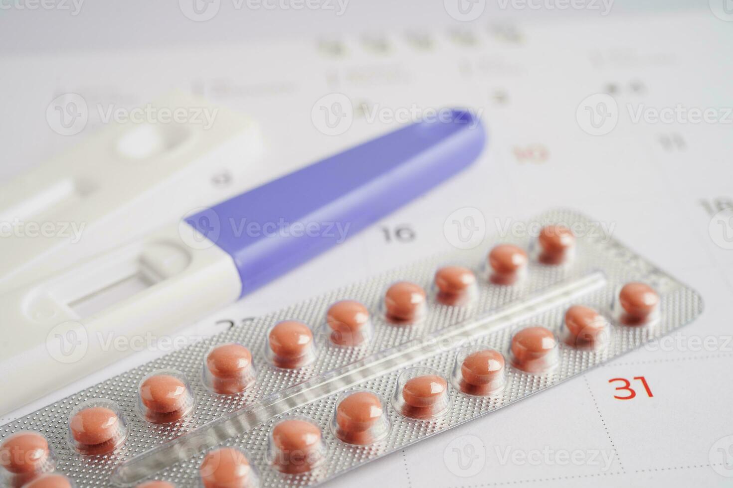 Pregnancy test with birth control pills for female on calendar, ovulation day. photo