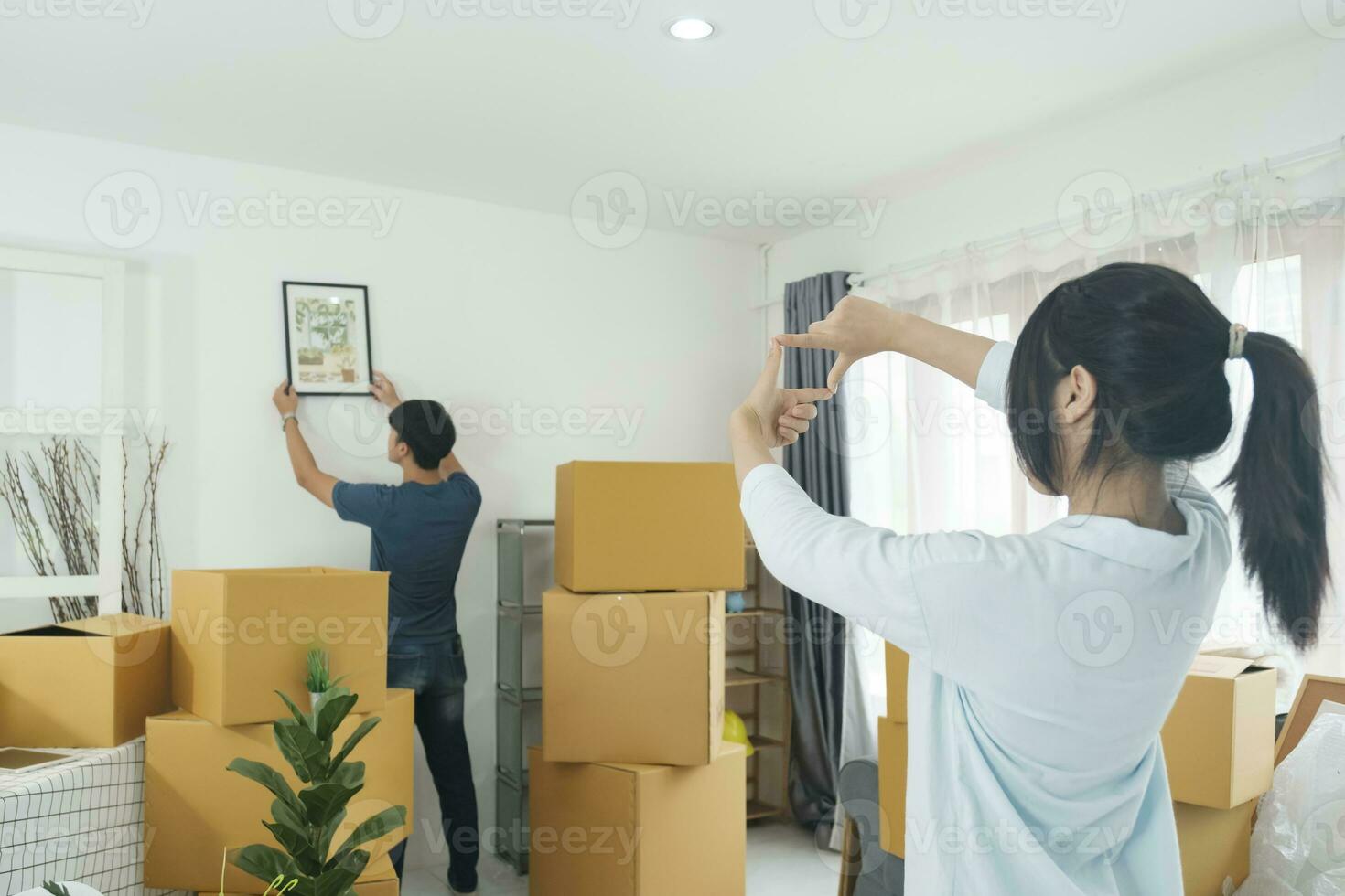 Man hanging picture on white wall in room. Interior design photo