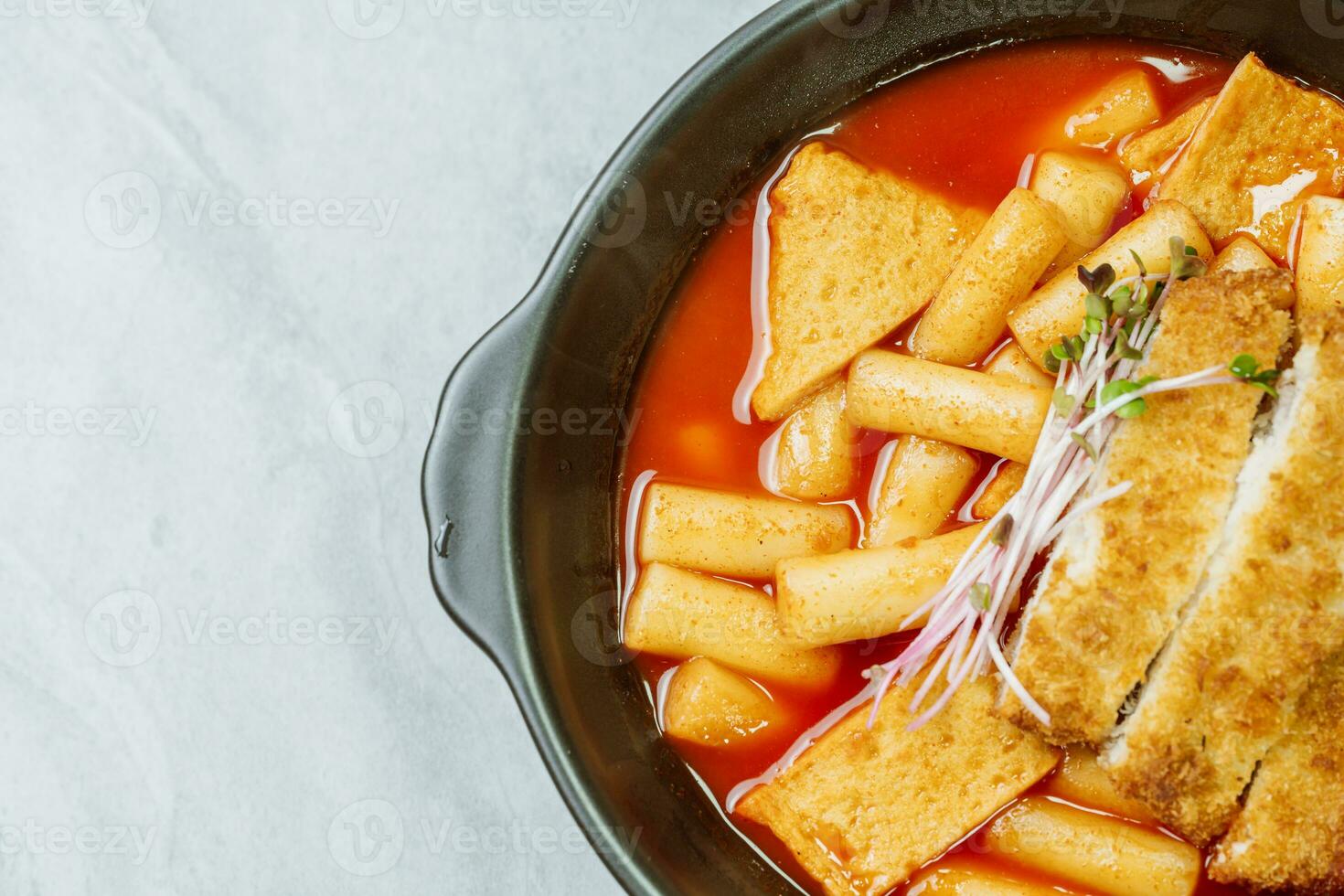 tteokbokki, un picante coreano plato de Cerdo chuletas, verduras, y pescado pasteles servido en un negro lámina. foto