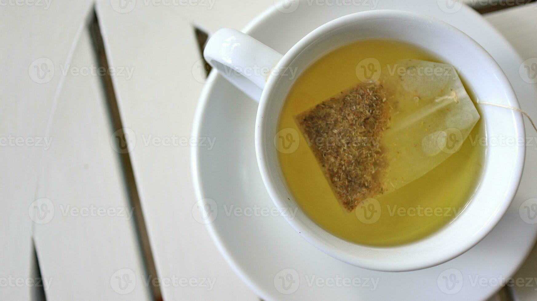 Healthy chamomile tea is poured into a white cup photo