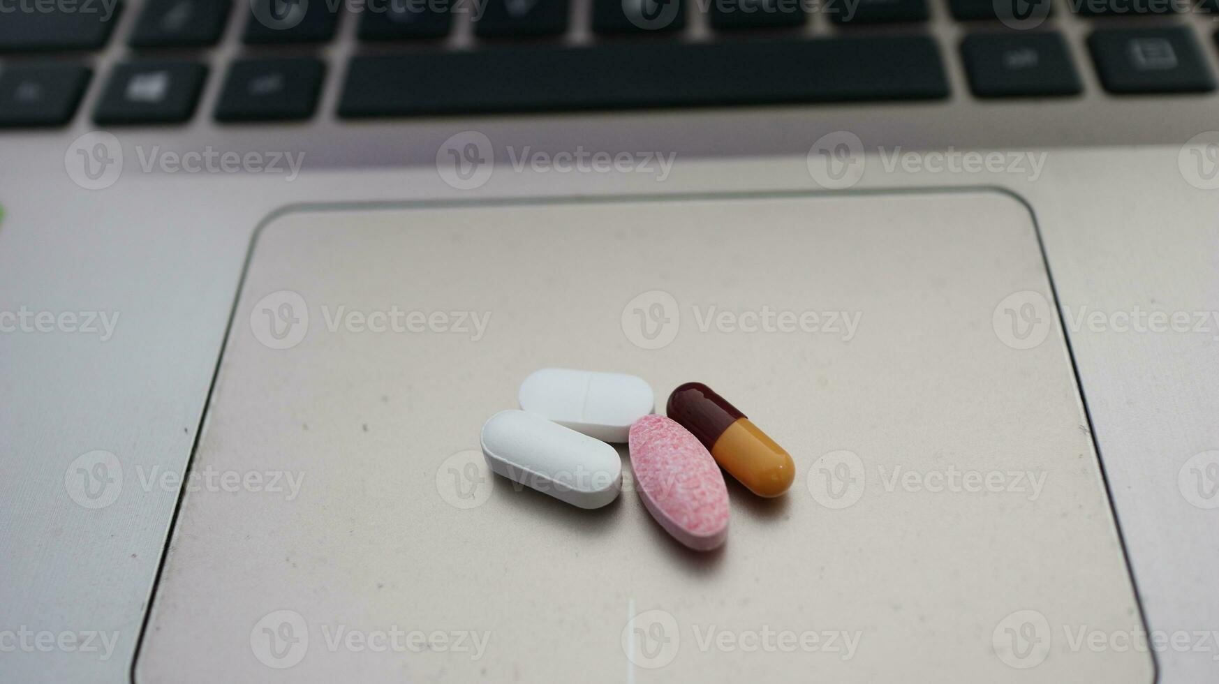 Various types of drugs, placed on a laptop keyboard photo