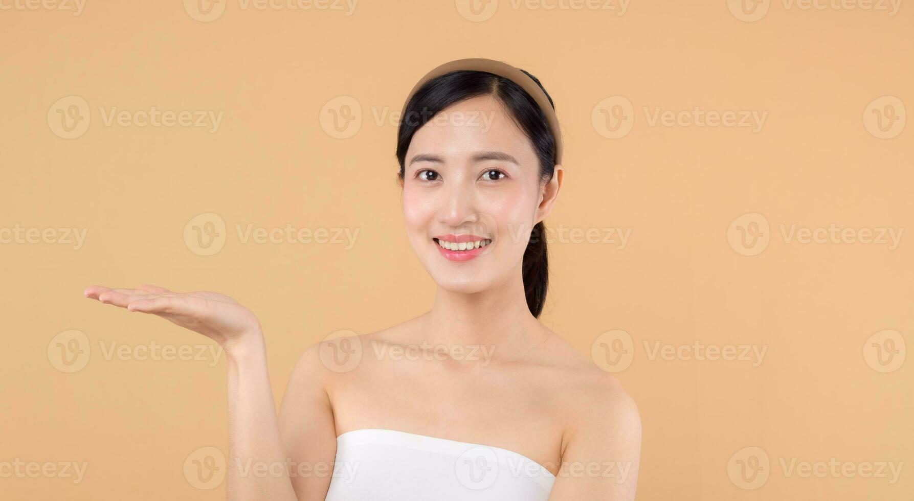 beauty asian young woman model with fresh glowing hydrated facial skin. girl person with natural makeup and healthy skin portrait isolated on beige studio background. spa treatment, skin care concept. photo