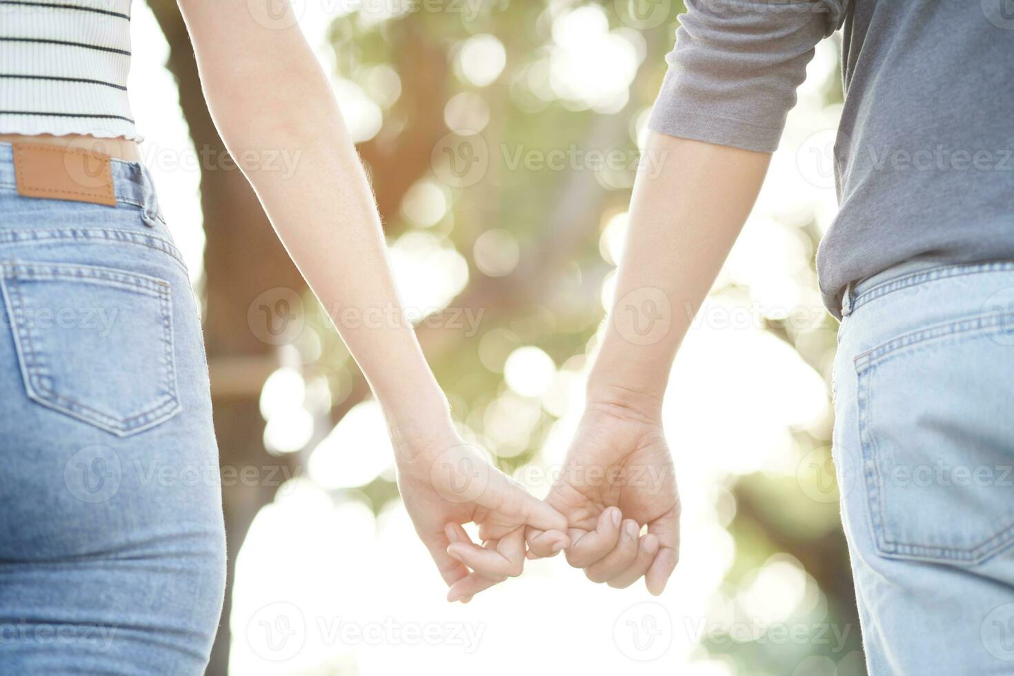 Couple lovers romantic holding hands towards with bright sun flare in public parks, or close up view in a conceptual image first love adolescent young relationship. lover photo