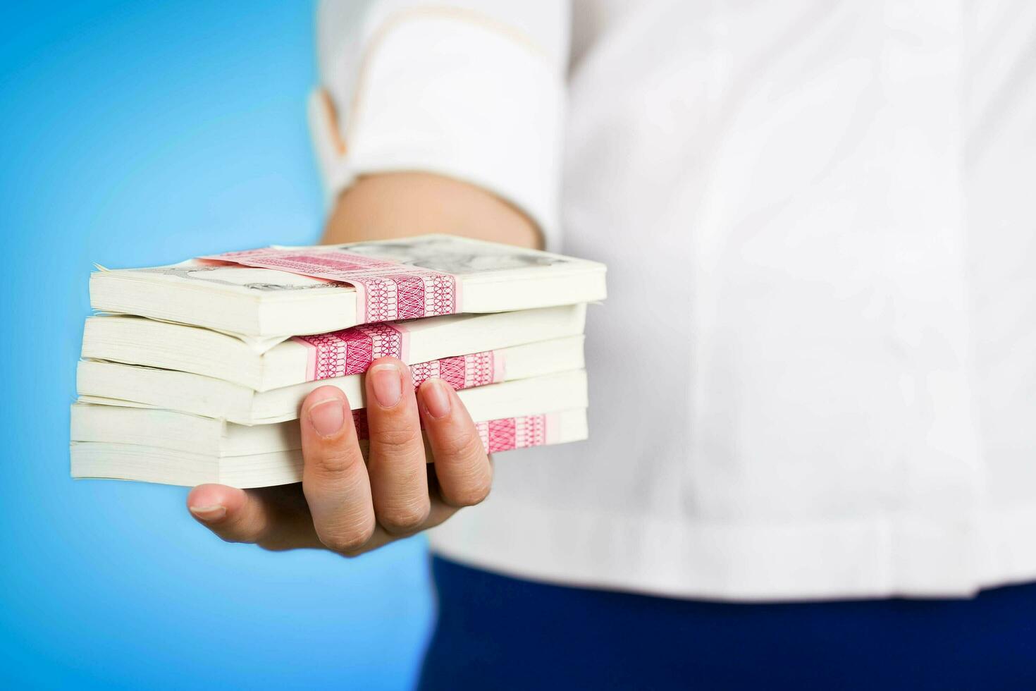 Female hand giving money pack on blue background. photo