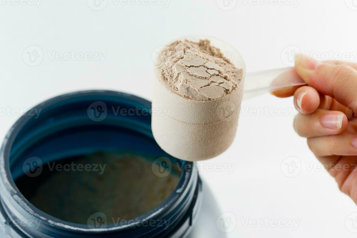 el mano aumento un cuchara medida suero proteína chocolate polvo para aptitud y culturismo ganando músculo. foto