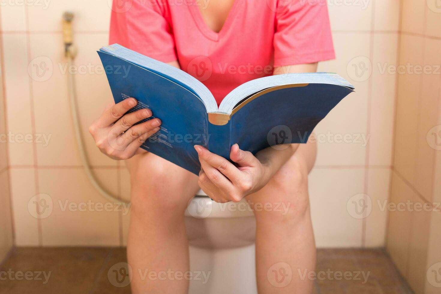 Young women reading a book while sitting in the toilet. photo