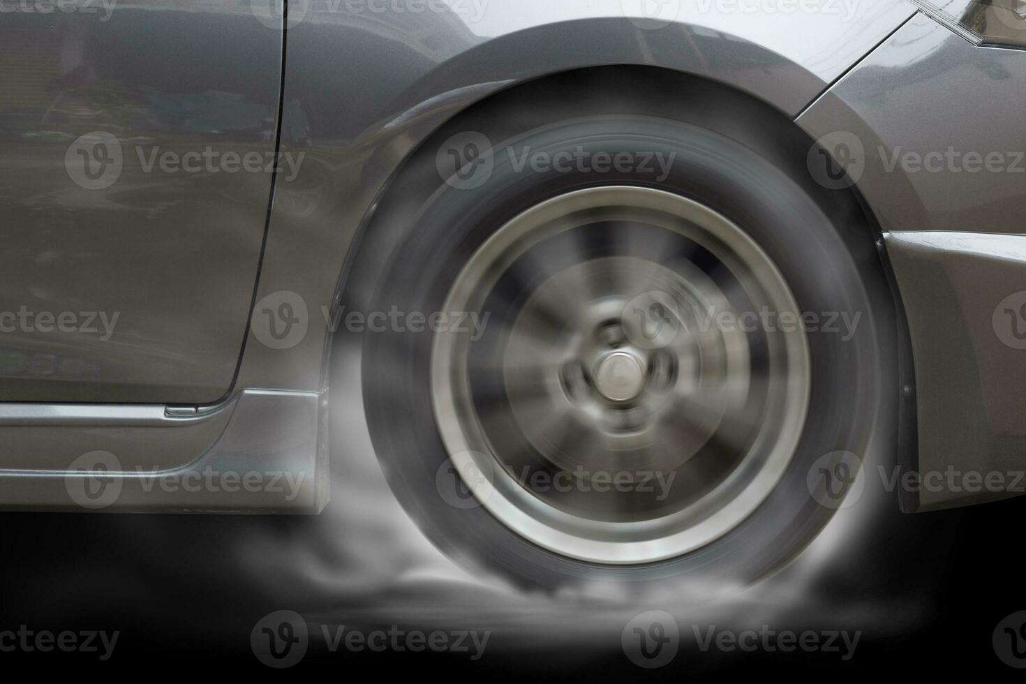 Grey Car racing spinning wheel burns rubber on floor. photo