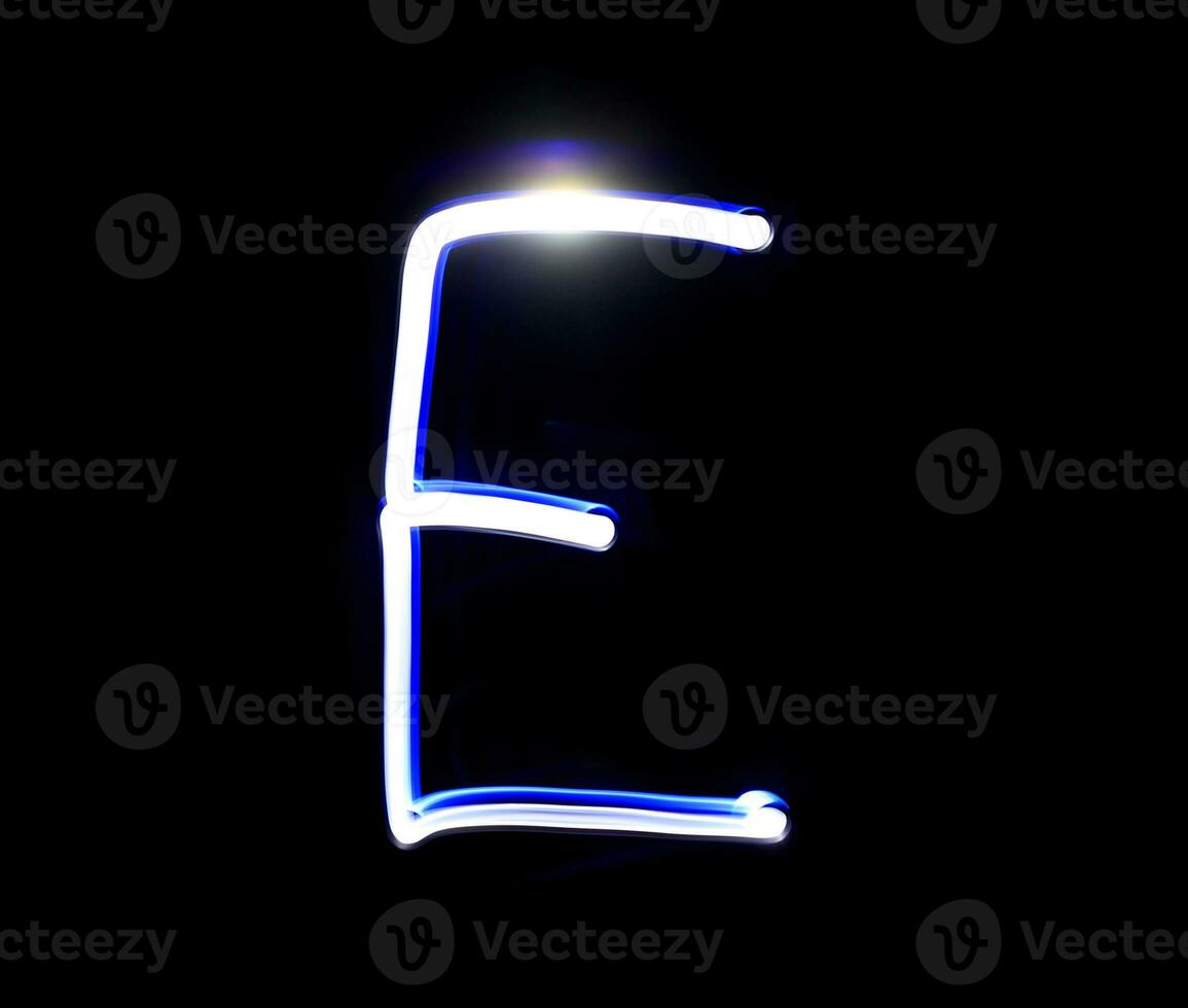 E Easy alphabet hand writing blue light  over black background. photo