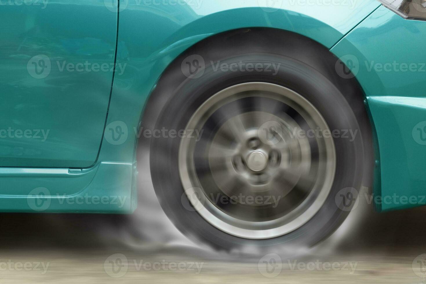Green car racing spinning wheel burns rubber on floor. photo