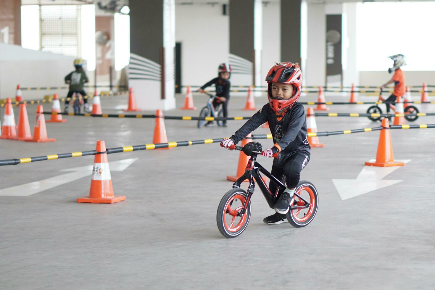 Depok-Indonesia, 29 07 2023 - Indonesian kids from 2-5 years old races on balance bike in a parking area, sportmanship training photo