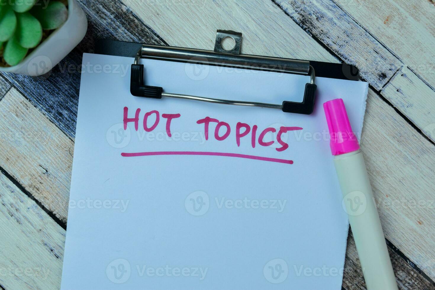 Concept of Hot Topics write on paperwork isolated on Wooden Table. photo