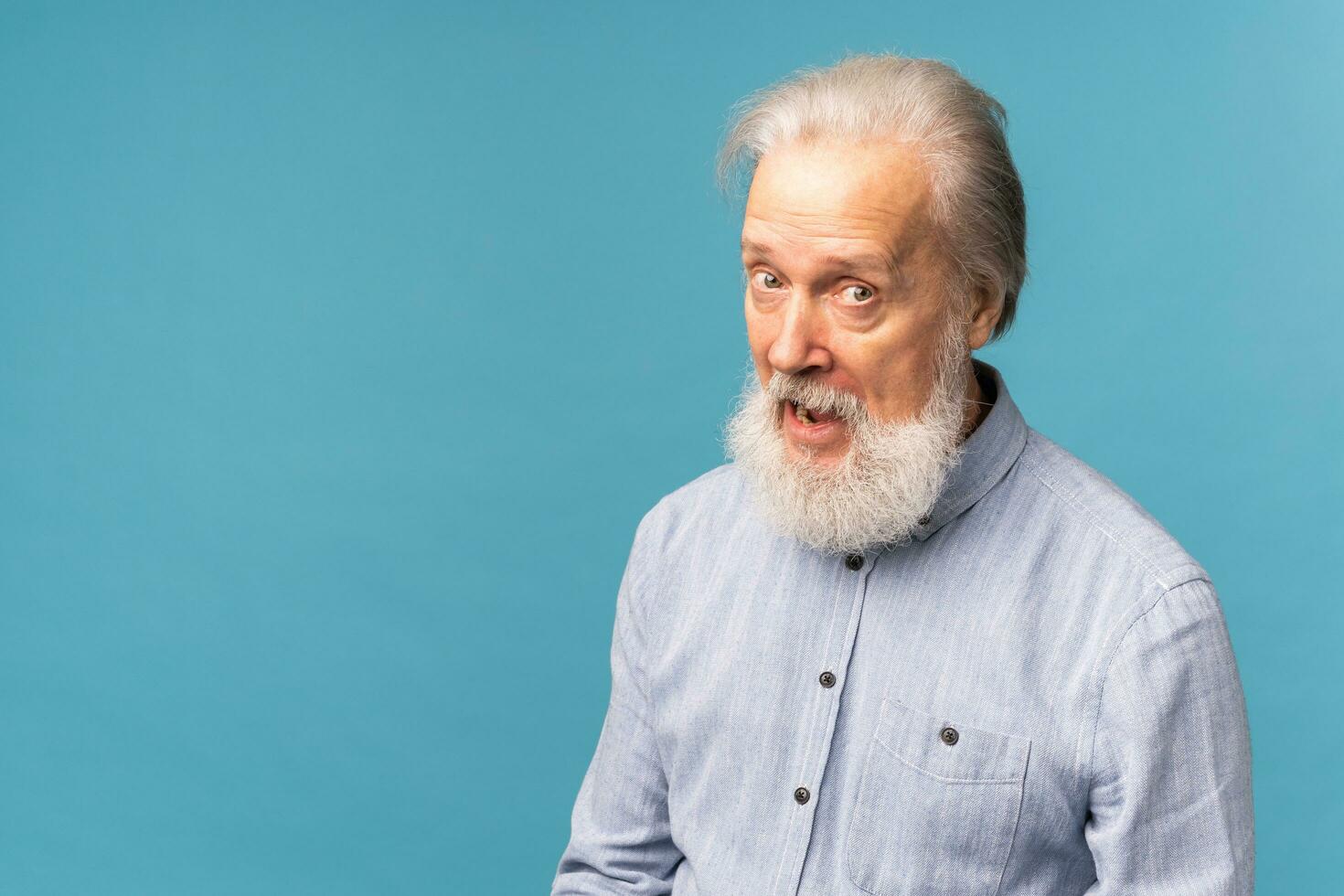 Portrait of shocked old man wear casual cloth open mouth isolated on blue color background with copy space - elderly people and emotion concept photo