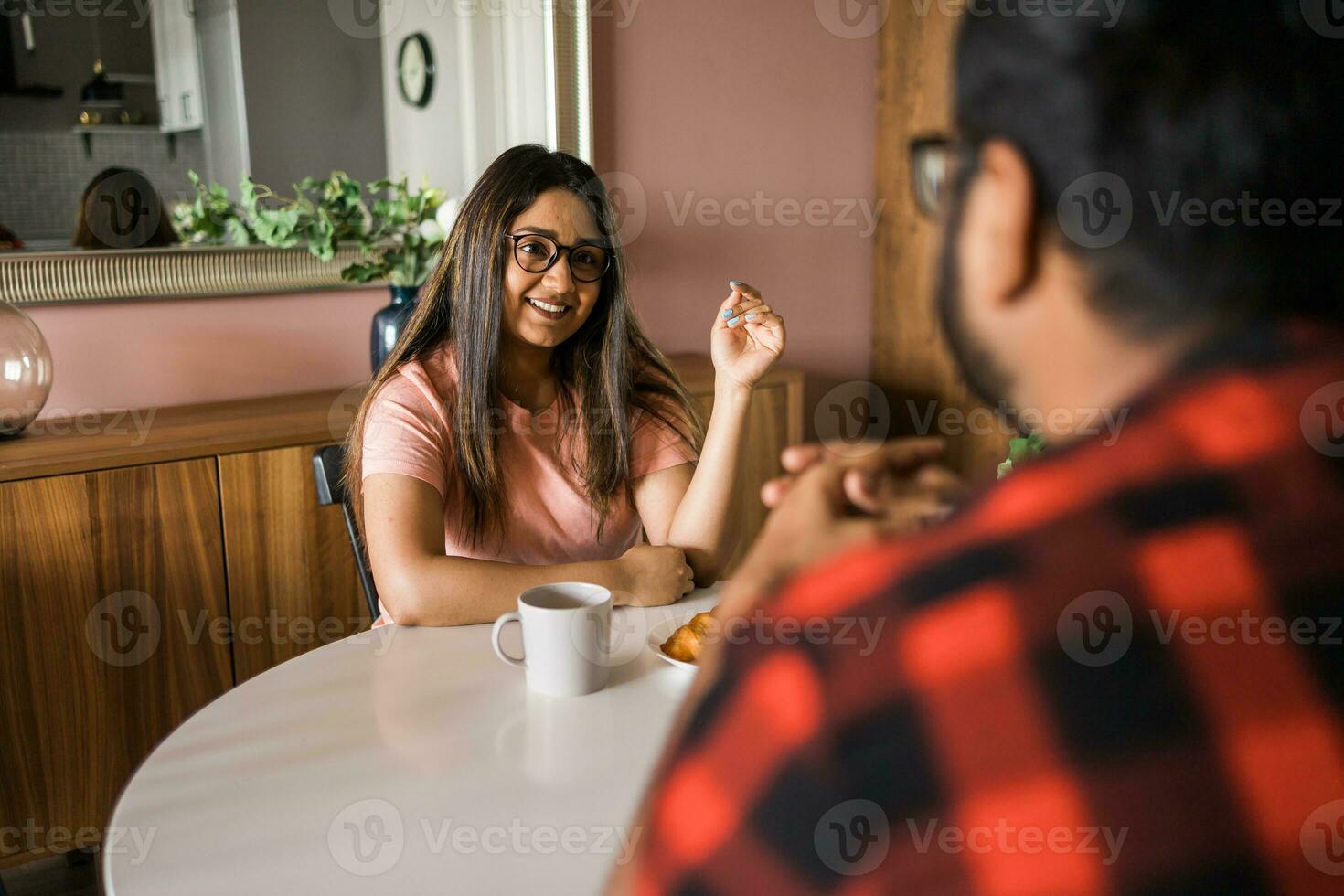 Young diverse loving couple eating croissant and talks together at home in breakfast time. Communication and relationship concept photo