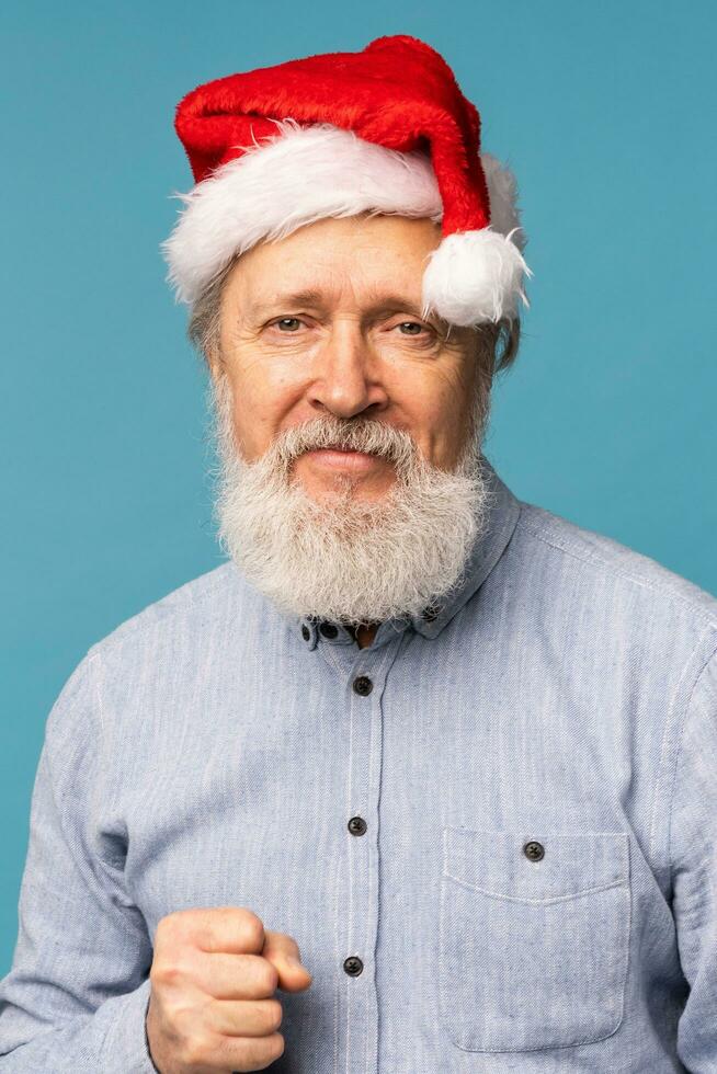 Happy confident cool old bearded Santa Claus winner raising fist celebrating triumph and success over blue background photo