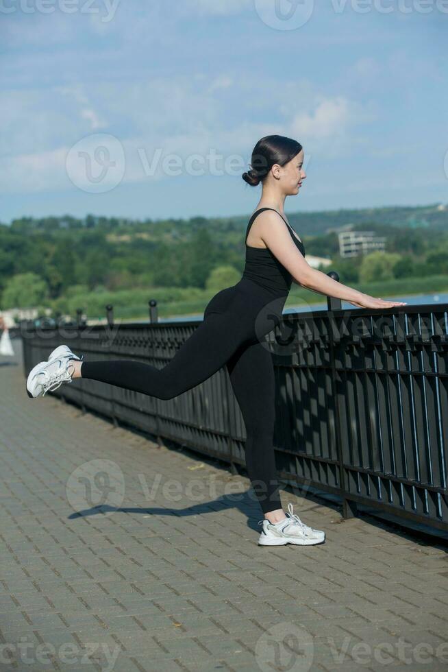 joven mujer en negro ropa de deporte hacer ejercicio al aire libre. aptitud  y sano estilo de vida concepto. el blanco niña lo hace Deportes en el  parque. 27299723 Foto de stock