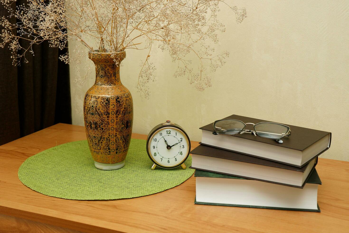 books, glasses, a vase with a bouquet and an alarm clock on the table, a pensioner's pastime photo