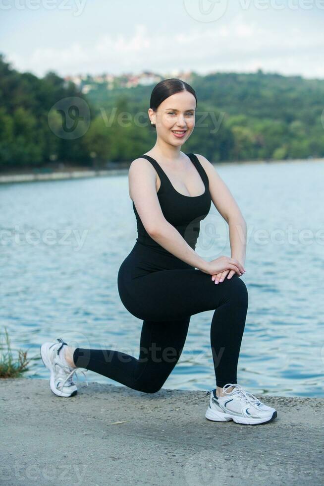 joven mujer en negro ropa de deporte hacer ejercicio al aire libre. aptitud  y sano estilo de vida concepto. el blanco niña lo hace Deportes en el  parque. 27300156 Foto de stock