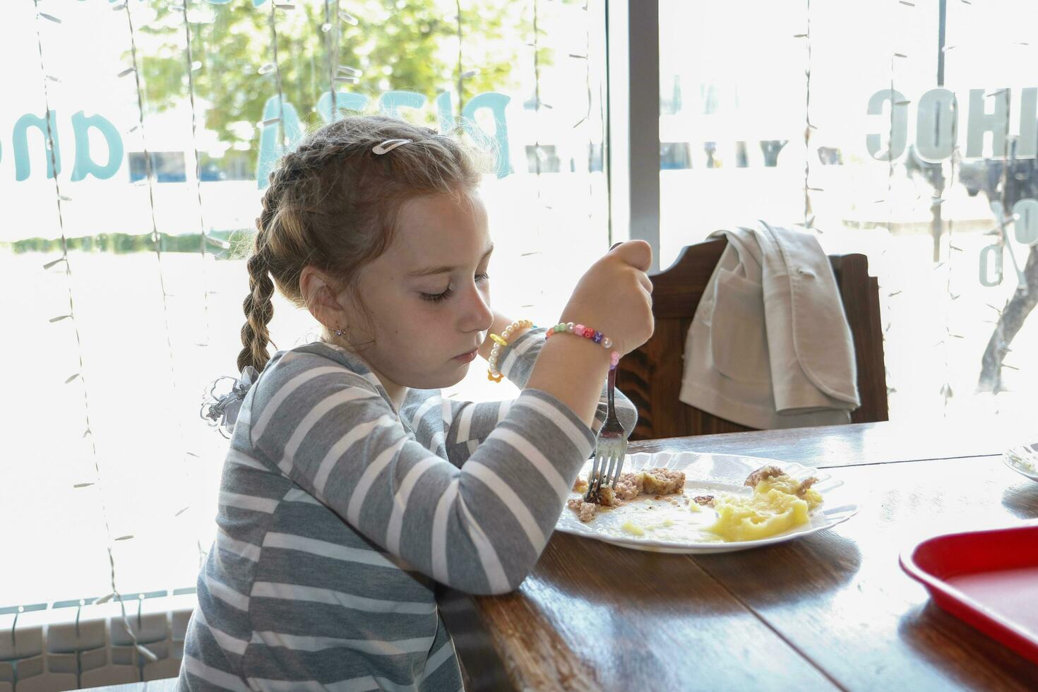 triste niña de mala gana teniendo almuerzo en un café foto