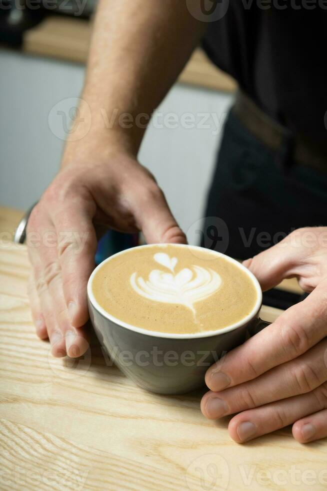 Barista hands serving coffee latte with art photo