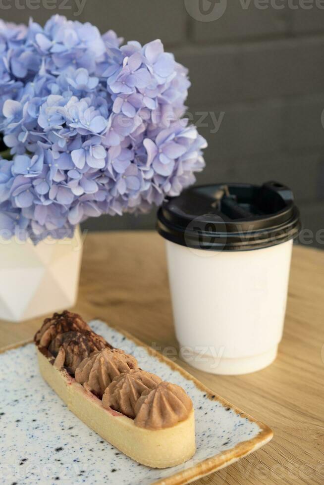 pastel con corteza corta Pastelería y crema en un de madera café mesa en un antecedentes de flores foto