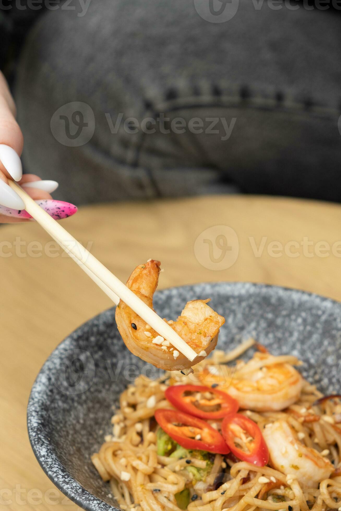Udon noodles with shrimp and fried vegetables in a bowl top view
