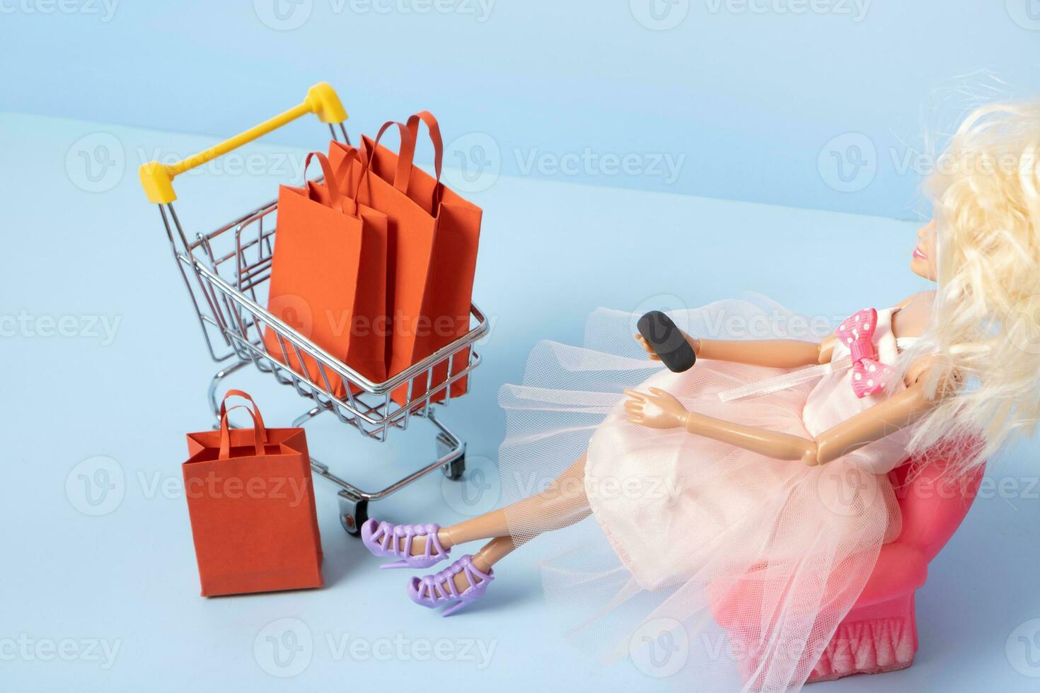 Doll with phone and supermarket basket with shopping bag. Shopping online concept photo