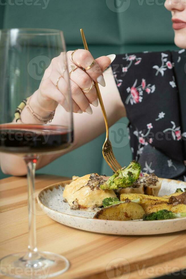 Close up of a fork in a woman's hand over a plate with delicious food in a restaurant photo