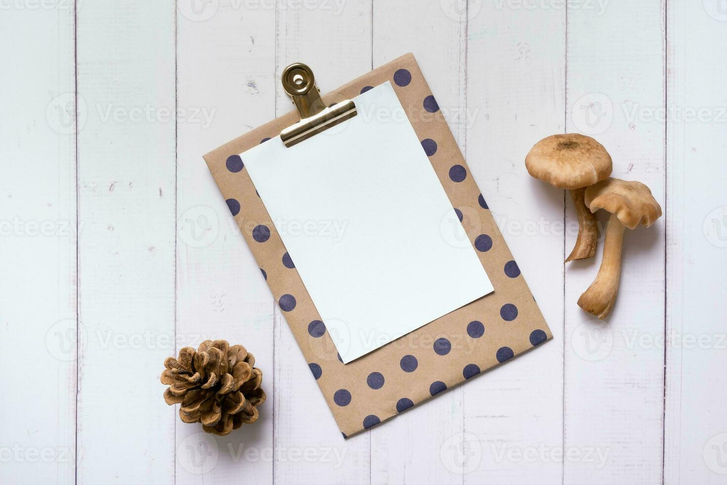Empty paper with mushrooms  and cone on wooden background top view photo