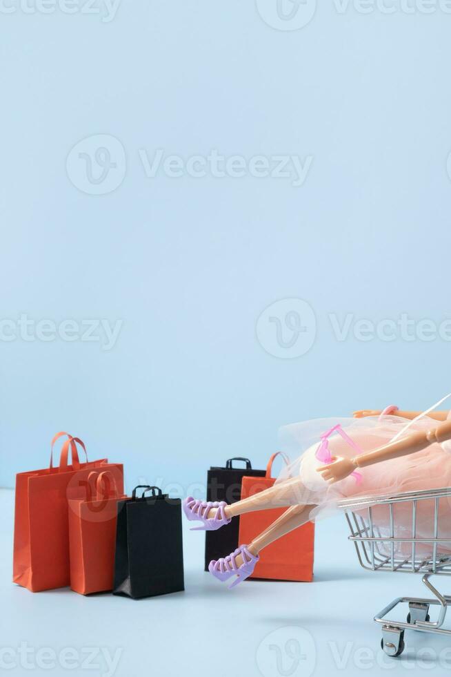 Doll in supermarket basket with shopping bag. Sale concept. Copy space. photo