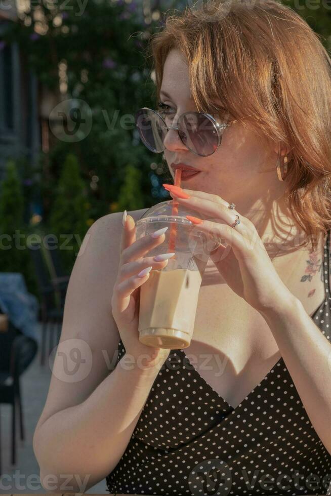 Ice latte coffee to go in female hand outdoors in evening sunshine photo