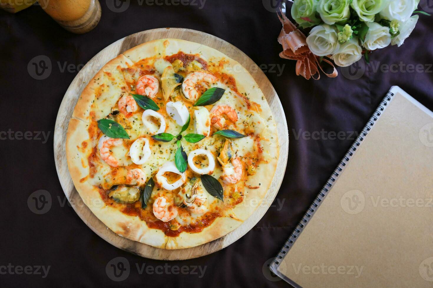 Delicious pizza with seafood on wooden stand, top view photo