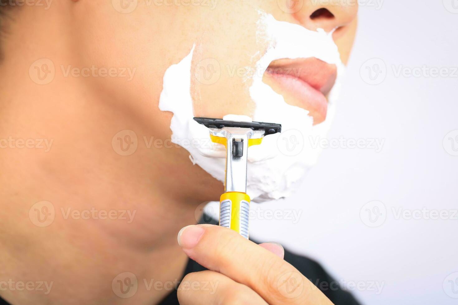 Close up young man shaving his face. photo