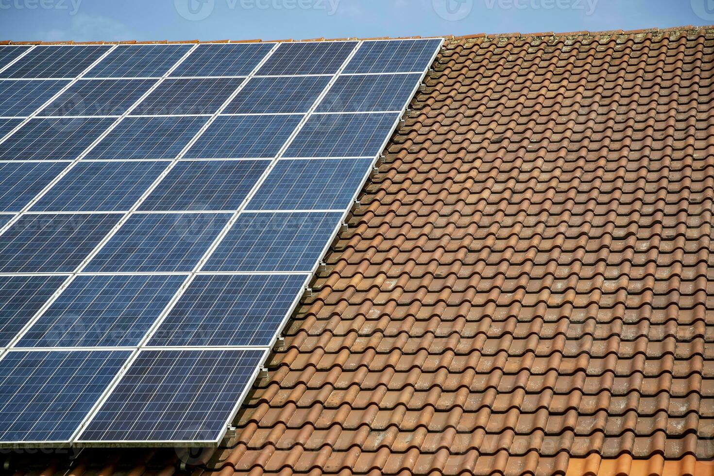 solar panels on roof of house. horizontal orientation, blue sky, gray panels on brown roof. photo