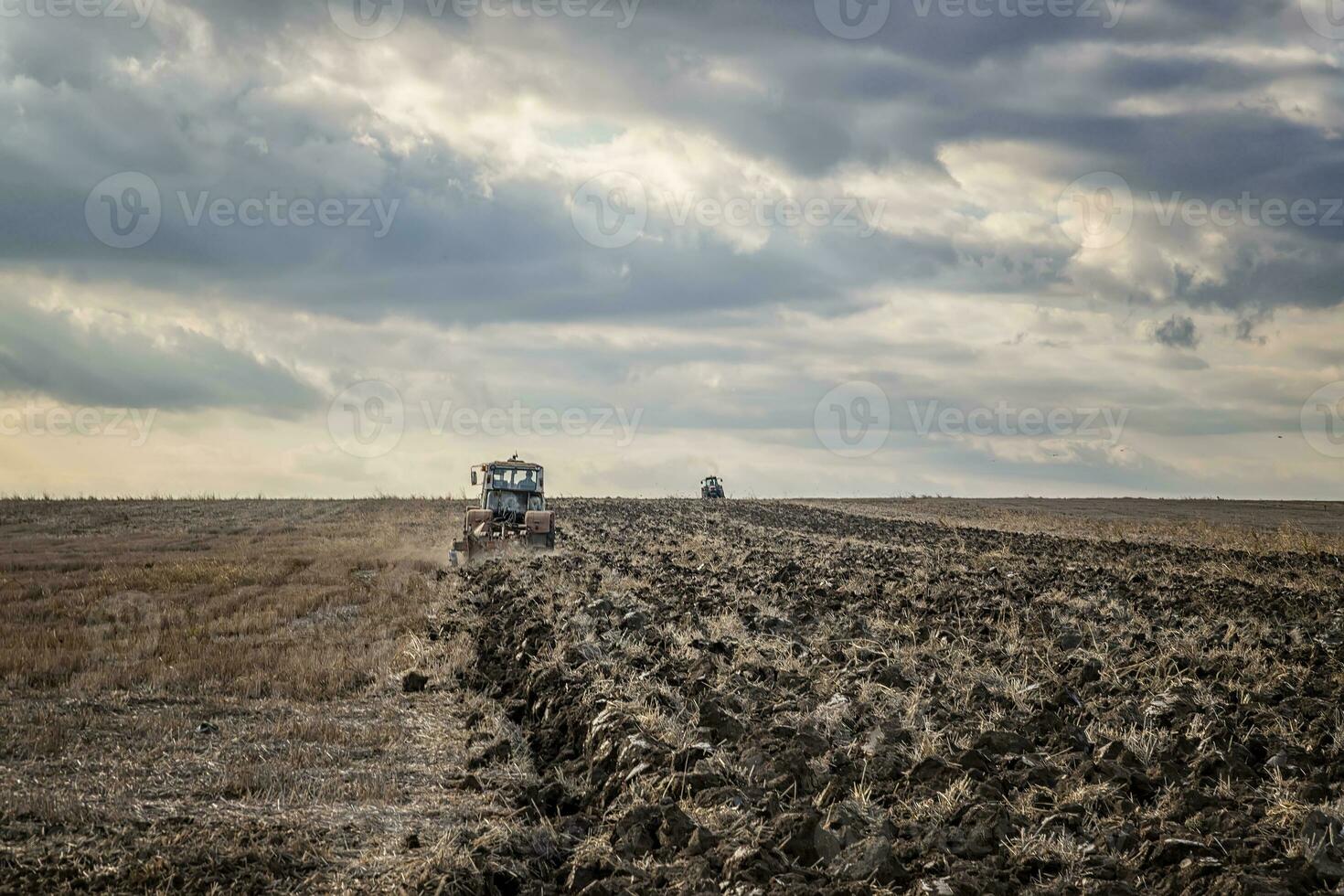 Day view of tractors plowing the soil in a mountain hill. Horizontal view photo