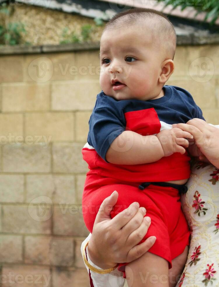 Close Up Shot of Cute Asian Pakistani 4 Months Old Baby Boy, Who is Enjoying at Home Garden at Luton City of England UK. Image Was Captured on July 23rd, 2023 photo