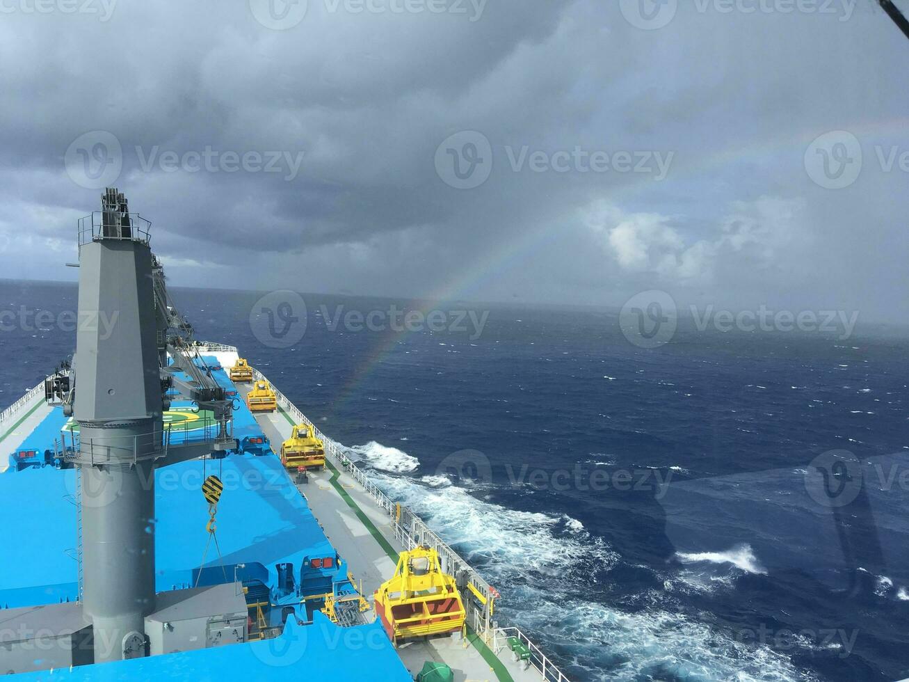 View from the bridge of the handymax bulk carrier to the holds and the rainbow during the day. Large cargo ship in the ocean photo