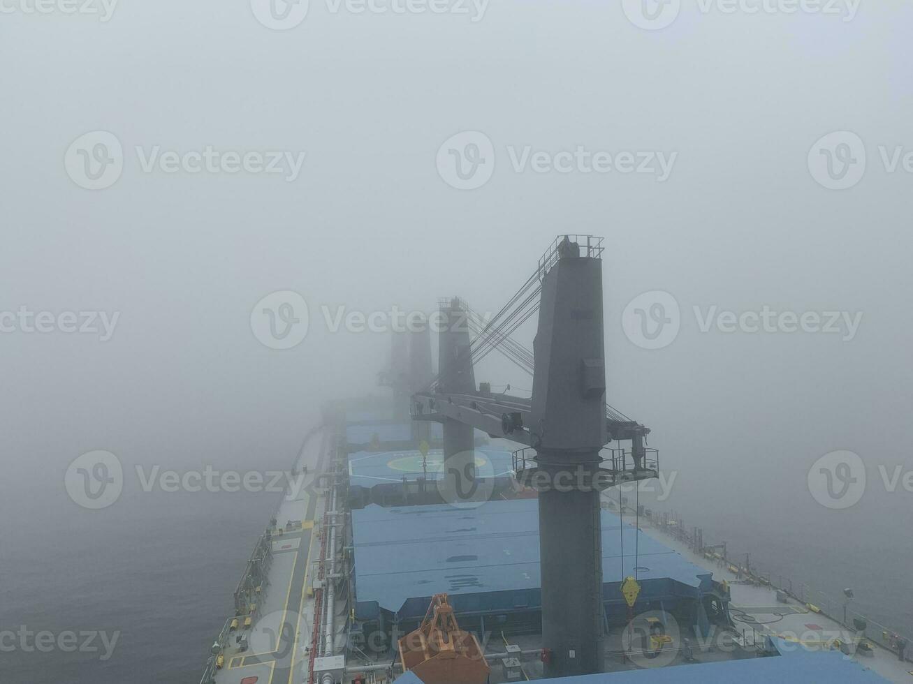 View from the bridge of the handymax bulk carrier to the holds in the fog. Large cargo ship in the river photo