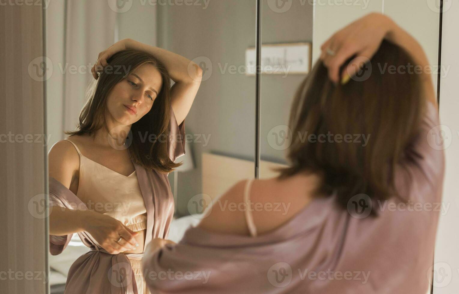 Happy morning portrait. Attractive young woman looking in mirror at her apartment - wake up and new day photo