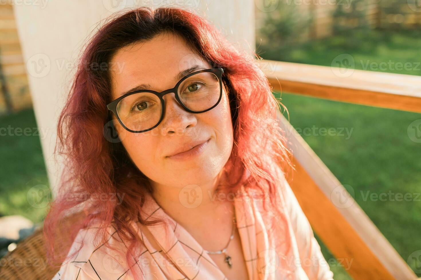 Outdoor close up portrait of young beautiful stylish curly girl in eyeglasses and sunlight. Sunny summer day light. photo