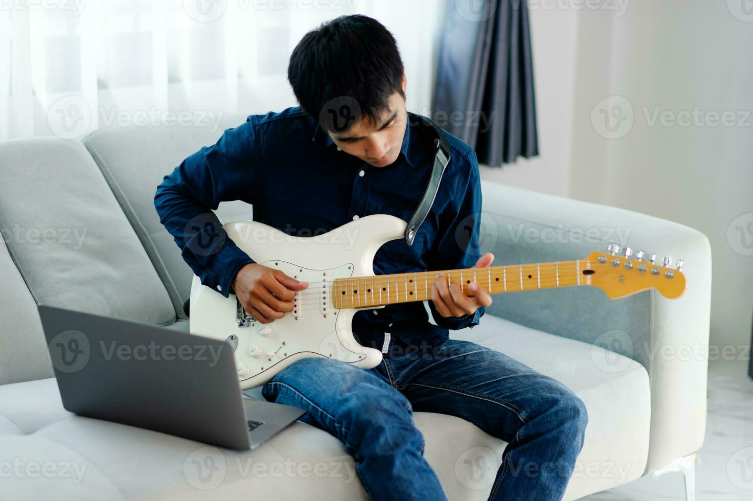 guitarrista jugando guitarra en sofá a hogar practicando guitarra a hogar relajarse por jugando de cuerda instrumentos foto