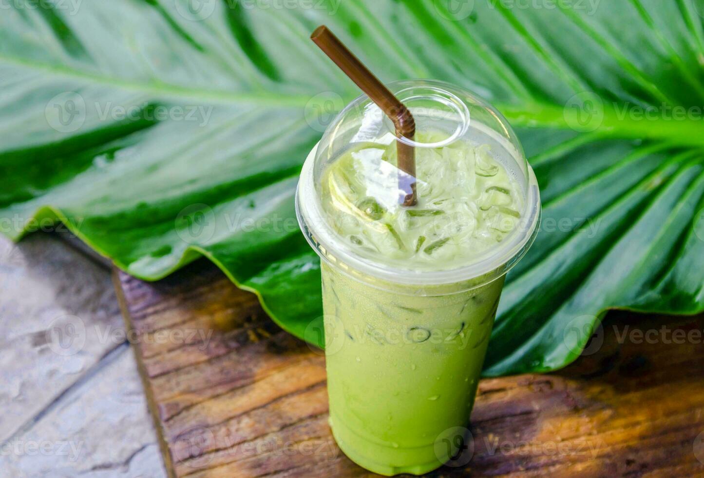 Green tea latte with ice in plastic cup and straw on wooden background.  Homemade Iced Matcha Latte Tea with Milk take away Stock Photo by  ©galitskaya 242393070